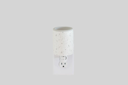 A white outlet wax warmer with a minimalistic design and speckled with dark dots.